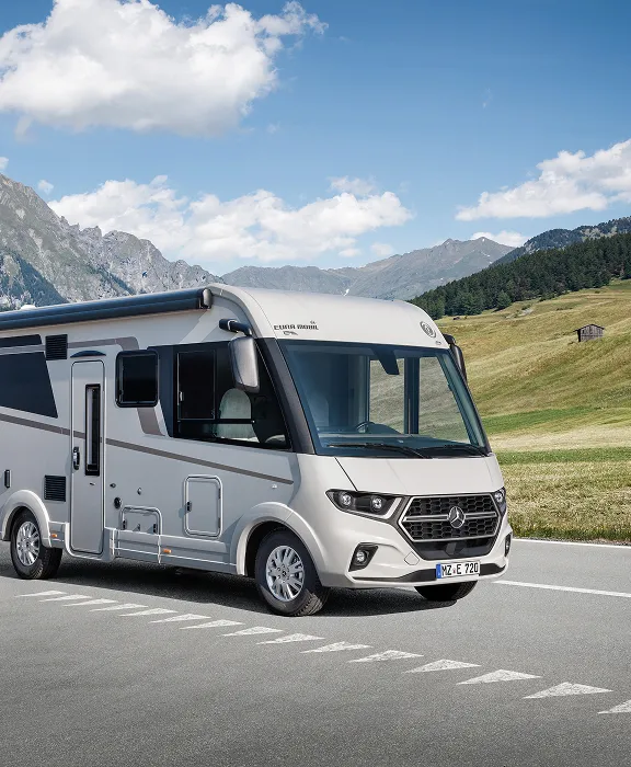 Vollintegriertes Eura Mobil Wohnmobil auf einer Passstraße vor einer imposanten Alpen-Bergkulisse.